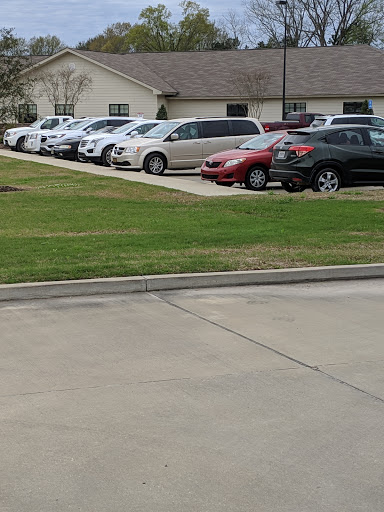 A view of a parking lot filled with various cars in front of a building.