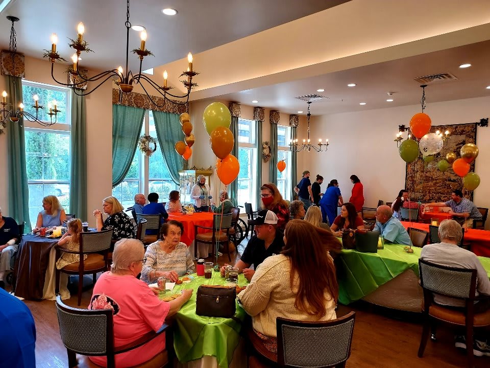 A lively indoor party with colorful balloons and guests seated at decorated tables.