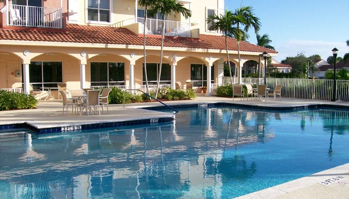 A serene poolside view at a tropical resort with palm trees.