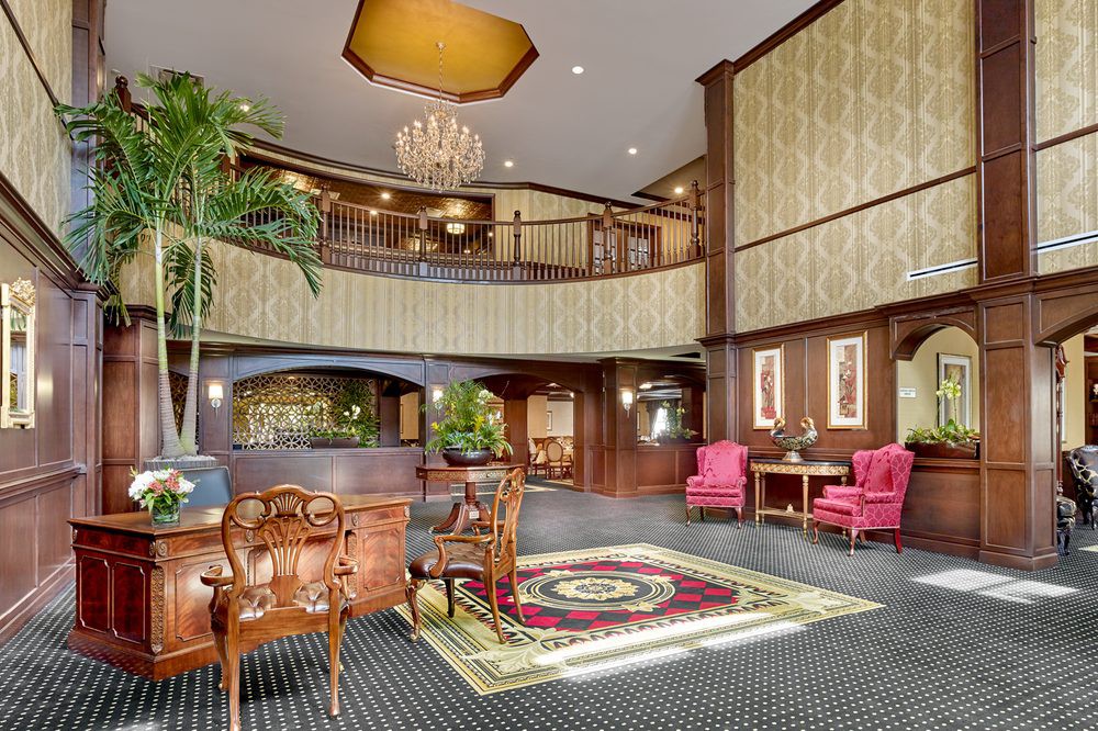 A spacious hotel lobby with classic interior design, featuring elegant furniture and a grand chandelier.