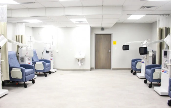 A clean, empty medical treatment room with chairs and equipment.