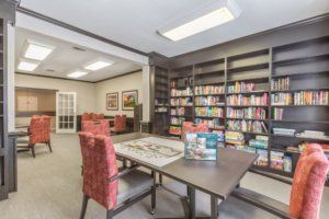 A cozy library room with bookshelves, a large table, and comfortable chairs.