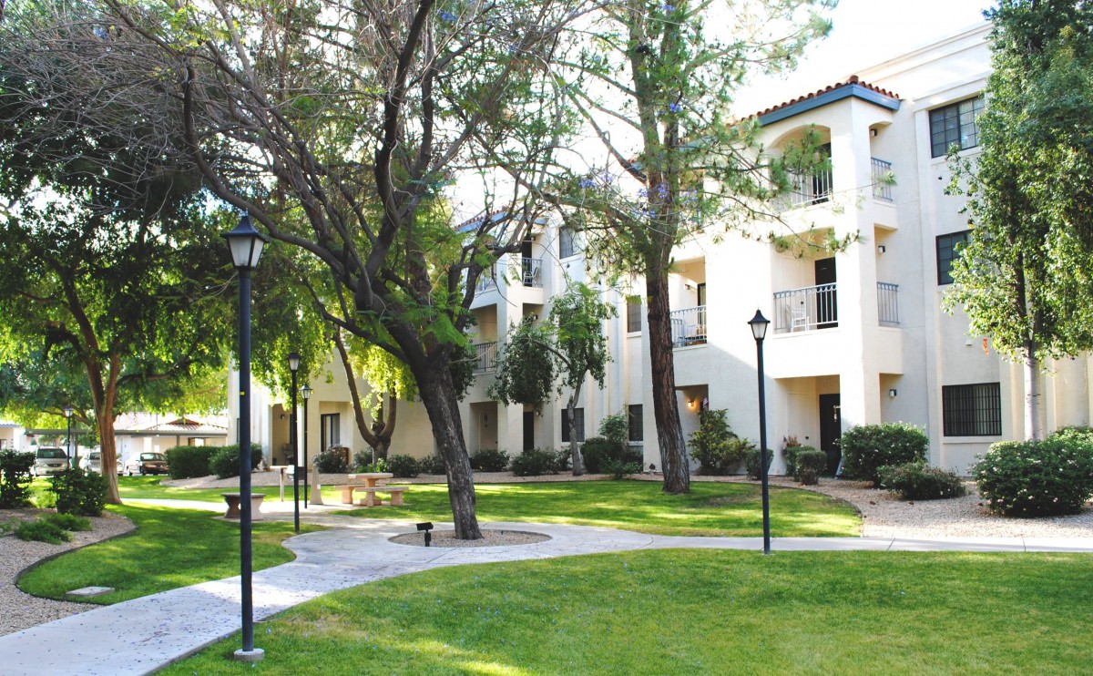A serene view of an apartment complex surrounded by lush greenery and winding pathways.
