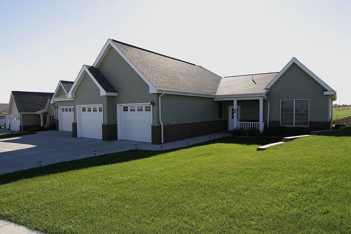 A suburban house with a well-maintained lawn and attached garages.