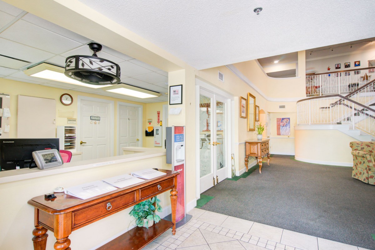 A bright and welcoming reception area with a front desk and adjoining hallway.