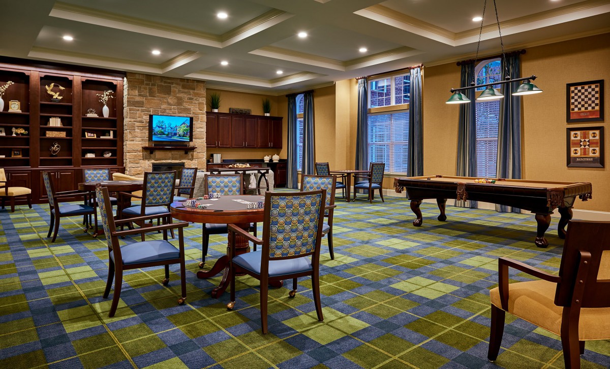 A spacious game room featuring a pool table, various seating areas, and a television.
