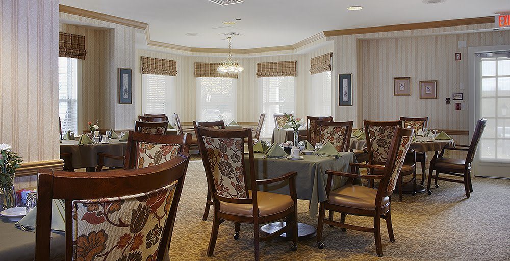An elegant dining room with ornate chairs and tables set near large windows.