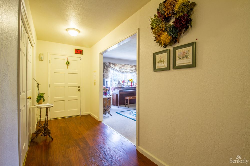 A cozy hallway with wall decorations, leading into a warmly lit room.
