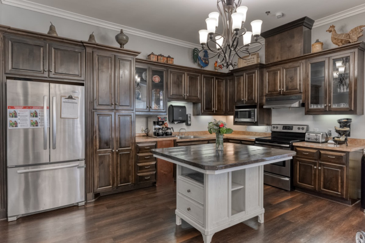 A modern kitchen with wooden cabinets, a central island, and a chandelier.