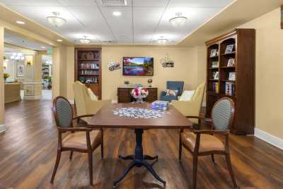 A cozy living room with a puzzle laid out on the table, surrounded by chairs and bookshelves.