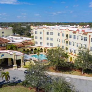 Aerial view of a resort hotel with a central swimming pool and landscaped surroundings.