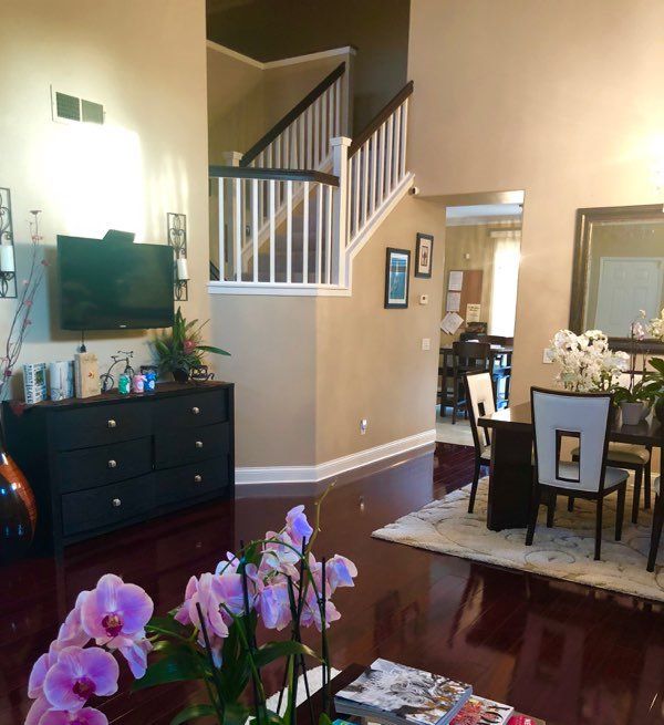 A spacious living and dining area with a staircase, featuring elegant furniture and vibrant decor.