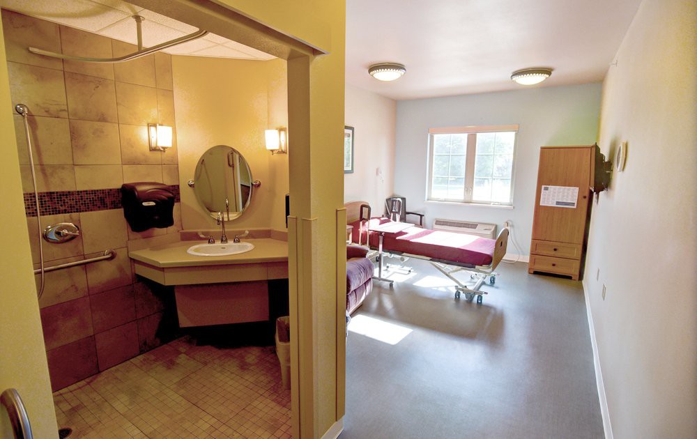 A well-lit hospital room with a patient bed and adjacent bathroom.