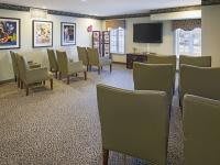 A small meeting room with rows of chairs facing a television, decorated with artwork on the walls.