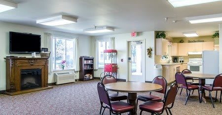 A cozy common area with a round table, chairs, and a popcorn machine.