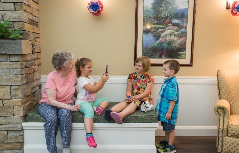 An elderly woman and three children enjoy a playful moment together indoors.