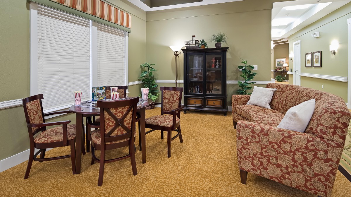 A cozy living room with classic furniture, including a dining table and chairs, a sofa, and a display cabinet.