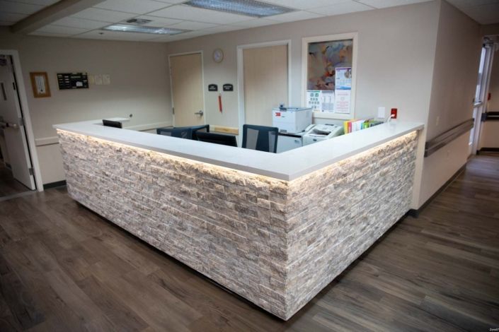 A modern office reception desk with stone texture and lighting.
