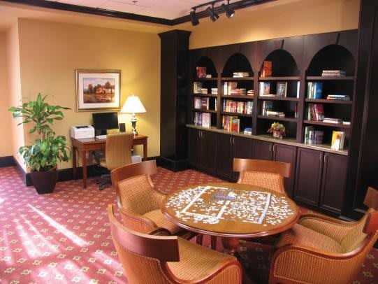 A cozy library space with a puzzle on the table, surrounded by bookshelves and comfortable chairs.