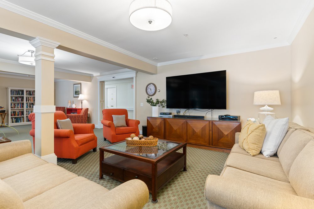 A cozy living room featuring orange armchairs, a large flat-screen TV, and a wooden coffee table.
