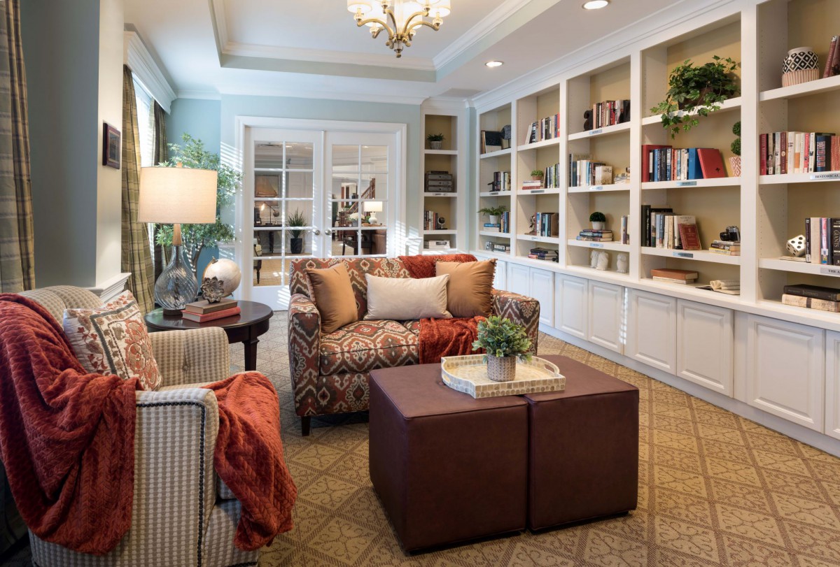 A cozy and elegant living room featuring a comfortable sofa, an armchair, and a well-organized bookshelf.