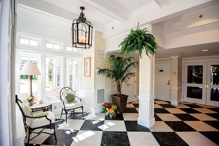 A bright and welcoming lobby with a checkered floor, stylish seating, and lush indoor plants.
