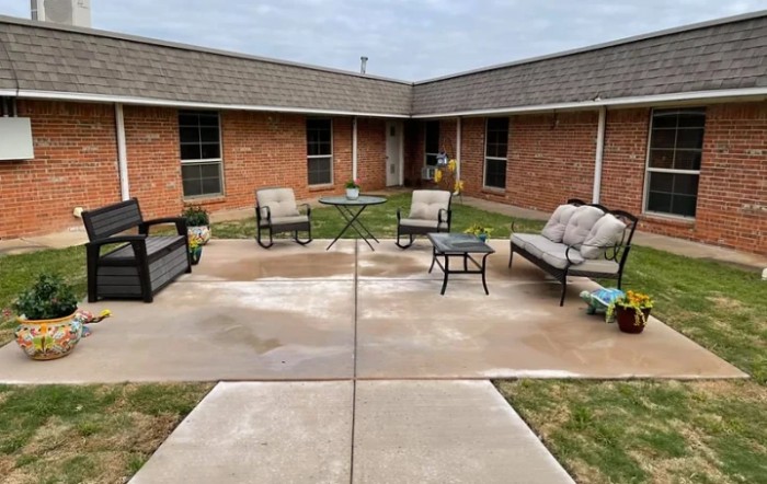 A cozy patio area with outdoor seating surrounded by a brick building.