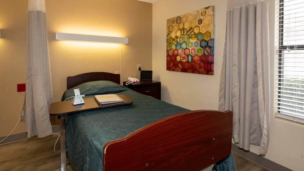 A cozy hotel room with a single bed and colorful artwork on the wall.