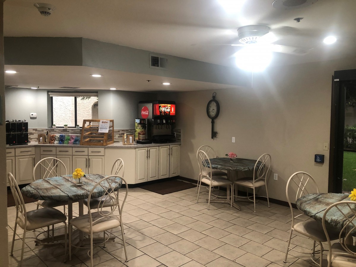 A cozy dining area with tables and chairs, featuring a beverage station in the corner.