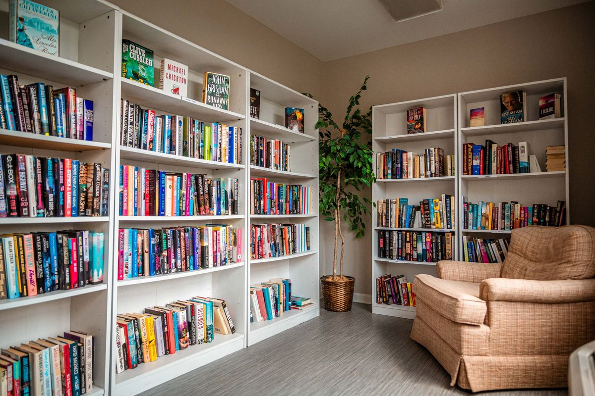 A cozy reading corner in a library with bookshelves and an armchair.