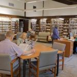 People reading and browsing in a library filled with books.