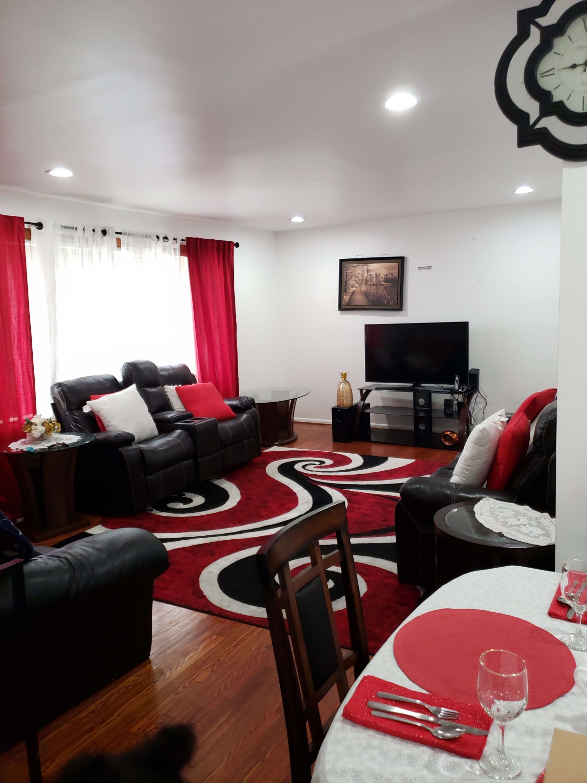 A cozy living room with a red and black color scheme, featuring comfortable sofas, a television, and a patterned carpet.
