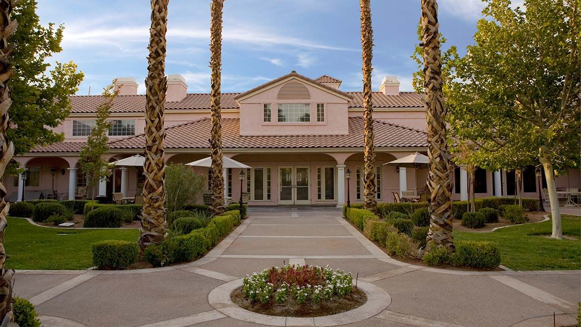 A large house with a pathway lined by palm trees and well-maintained landscaping.