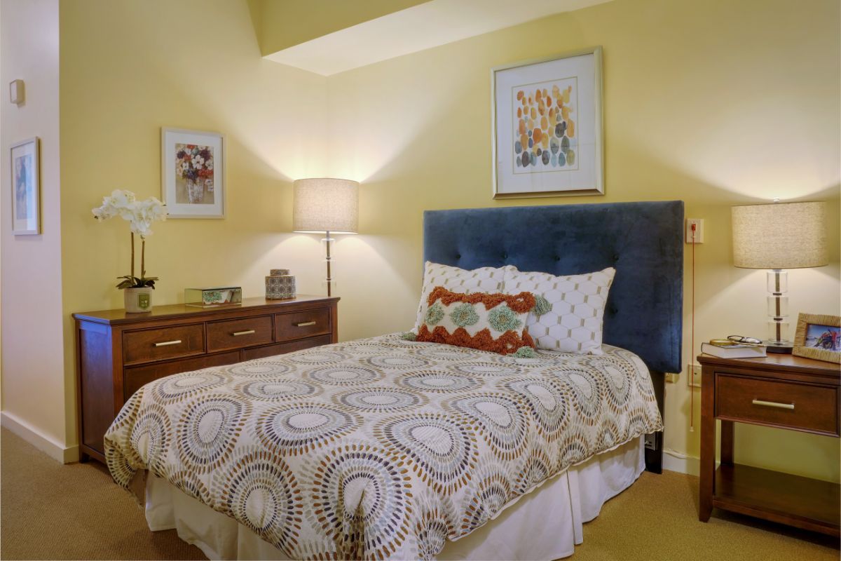 A cozy bedroom with a decorative bedspread and elegant artwork.