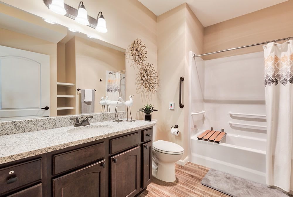 A modern bathroom featuring a granite countertop, elegant decor, and a bathtub with wood accents.