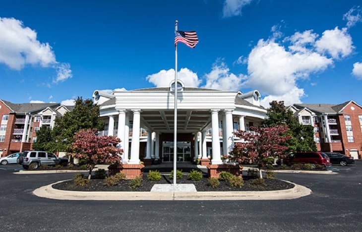 A grand building entrance with white columns and an American flag on a sunny day.