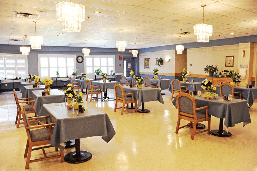 A spacious dining area with neatly arranged tables and chairs, adorned with elegant chandeliers.