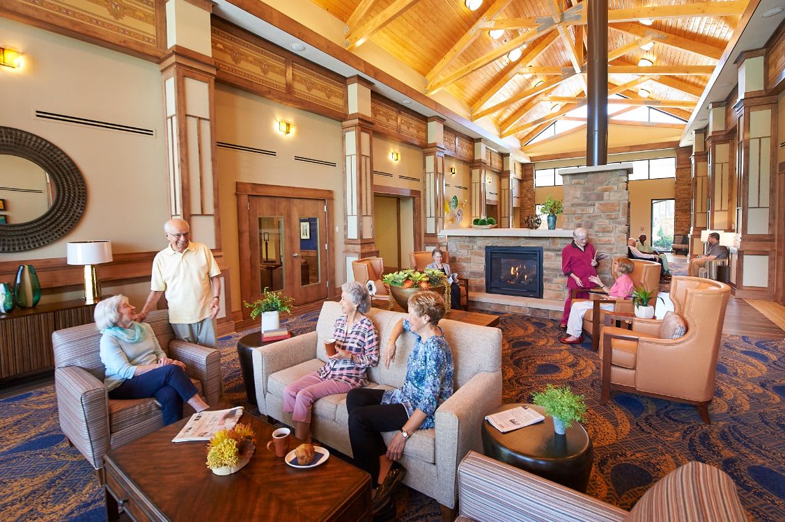 A cozy lounge area with seniors socializing near a fireplace.
