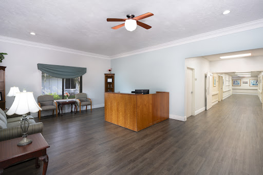 A bright and spacious reception area featuring a wooden front desk, comfortable seating, and modern decor.