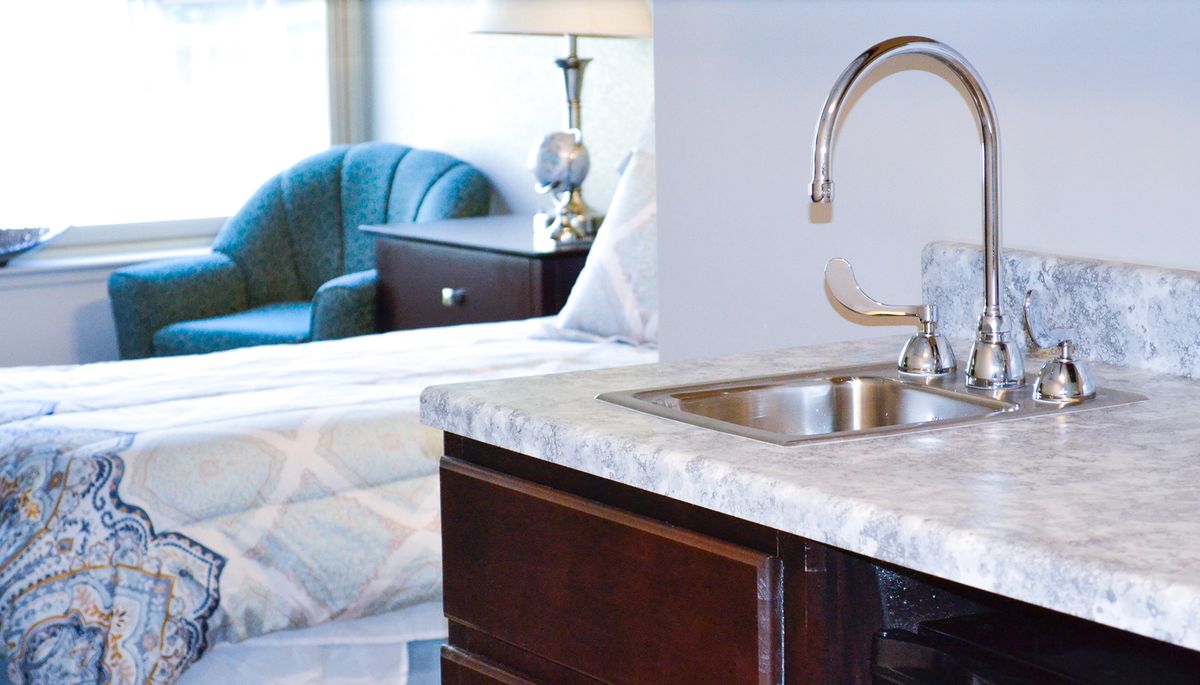 Modern kitchen area with a sleek countertop and shiny faucet, adjacent to a cozy living space.