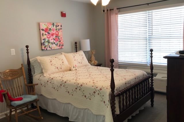 A cozy bedroom with floral bedding and a wooden bed frame.