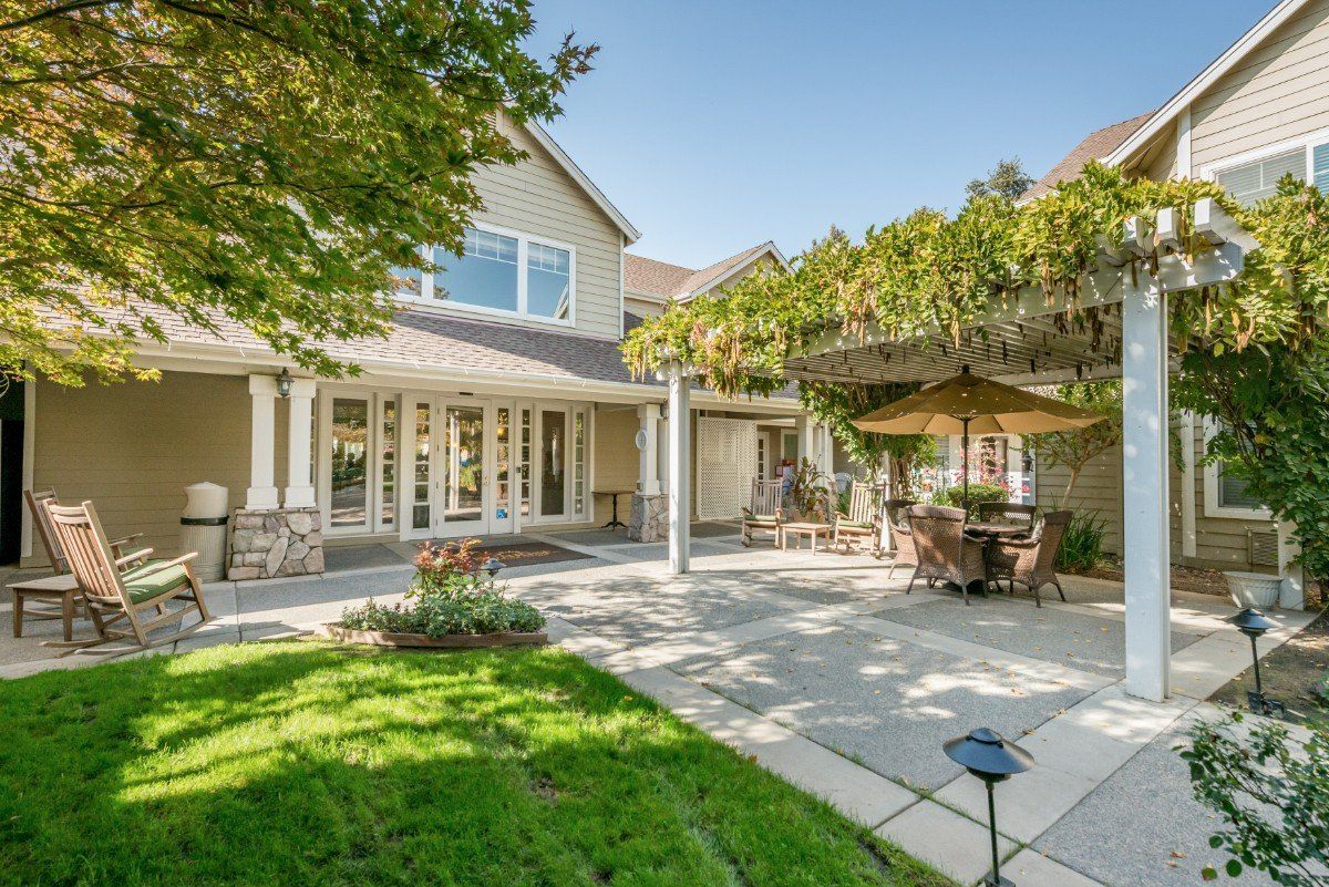 A beautiful backyard patio area with outdoor dining and lush greenery on a sunny day.