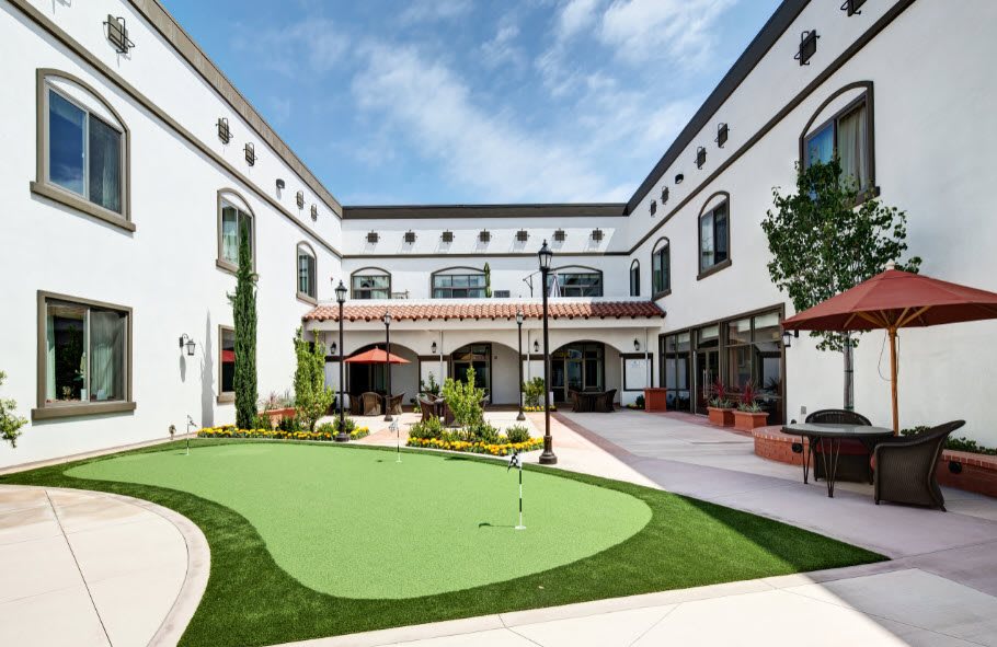 A modern courtyard featuring a putting green surrounded by elegant architecture.