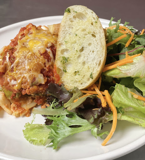 A delicious serving of lasagna accompanied by a fresh salad and garlic bread.