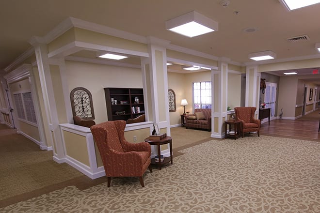 A cozy lounge area with armchairs, shelves, and decorative elements in a well-lit interior space.