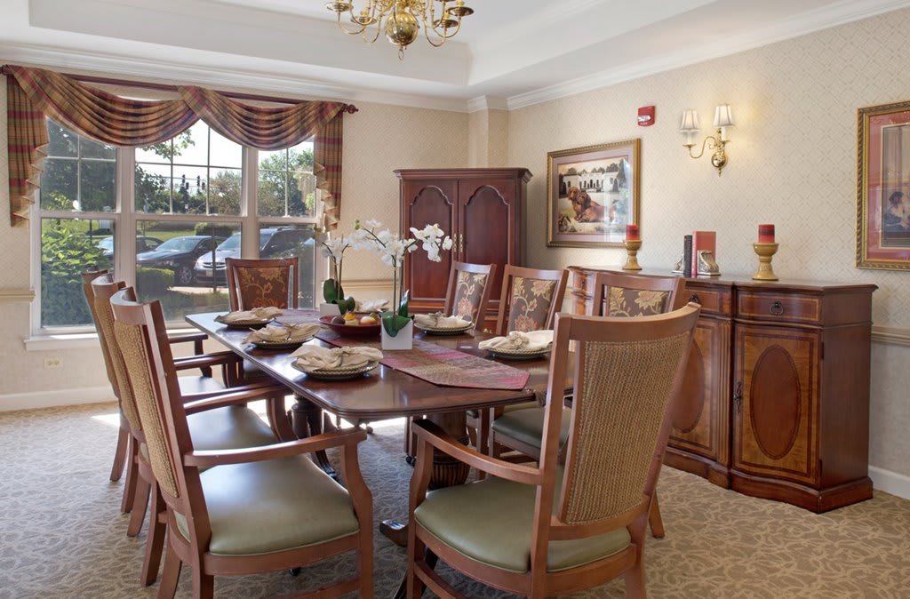 A well-appointed dining room with a large table and upholstered chairs, adorned with a chandelier and decorative elements.