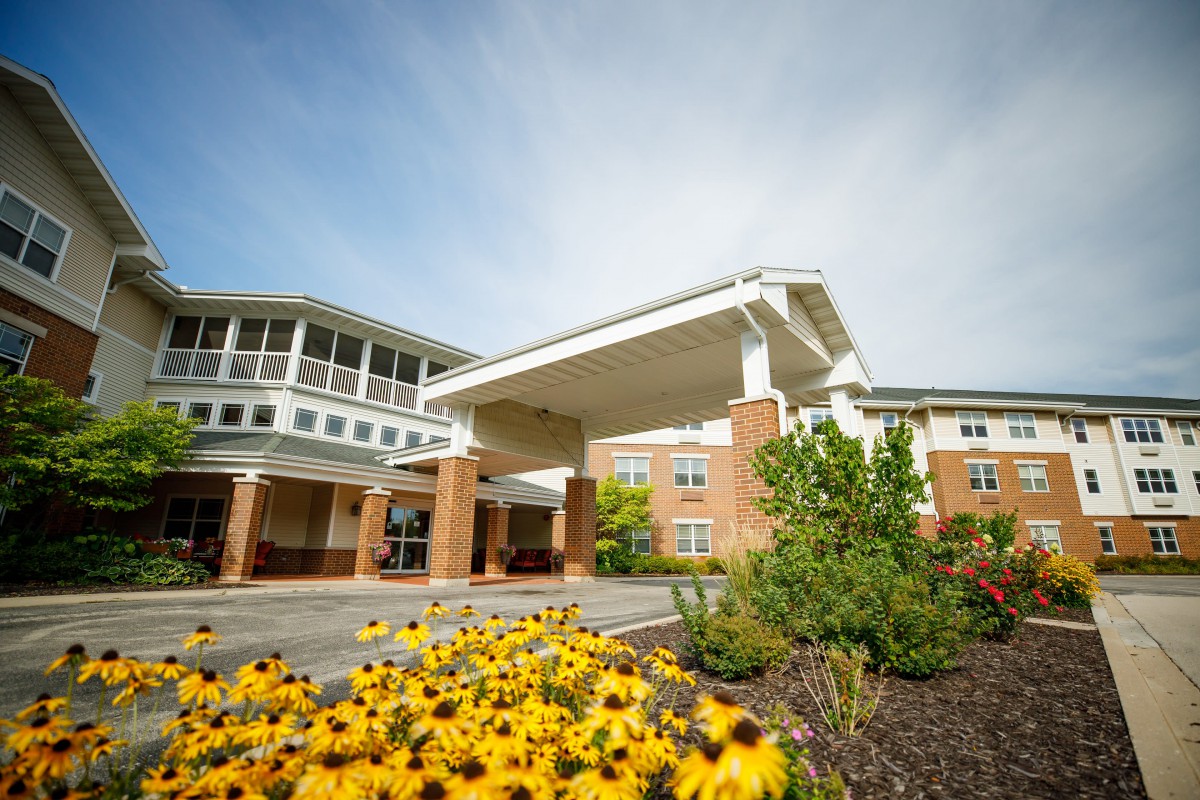 A well-landscaped building entrance with vibrant yellow flowers in the foreground.