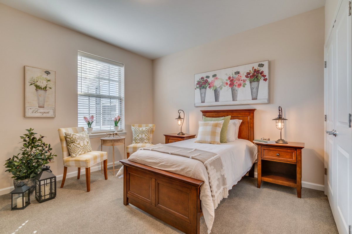 A cozy bedroom with a single bed, wooden furniture, and decorative touches.