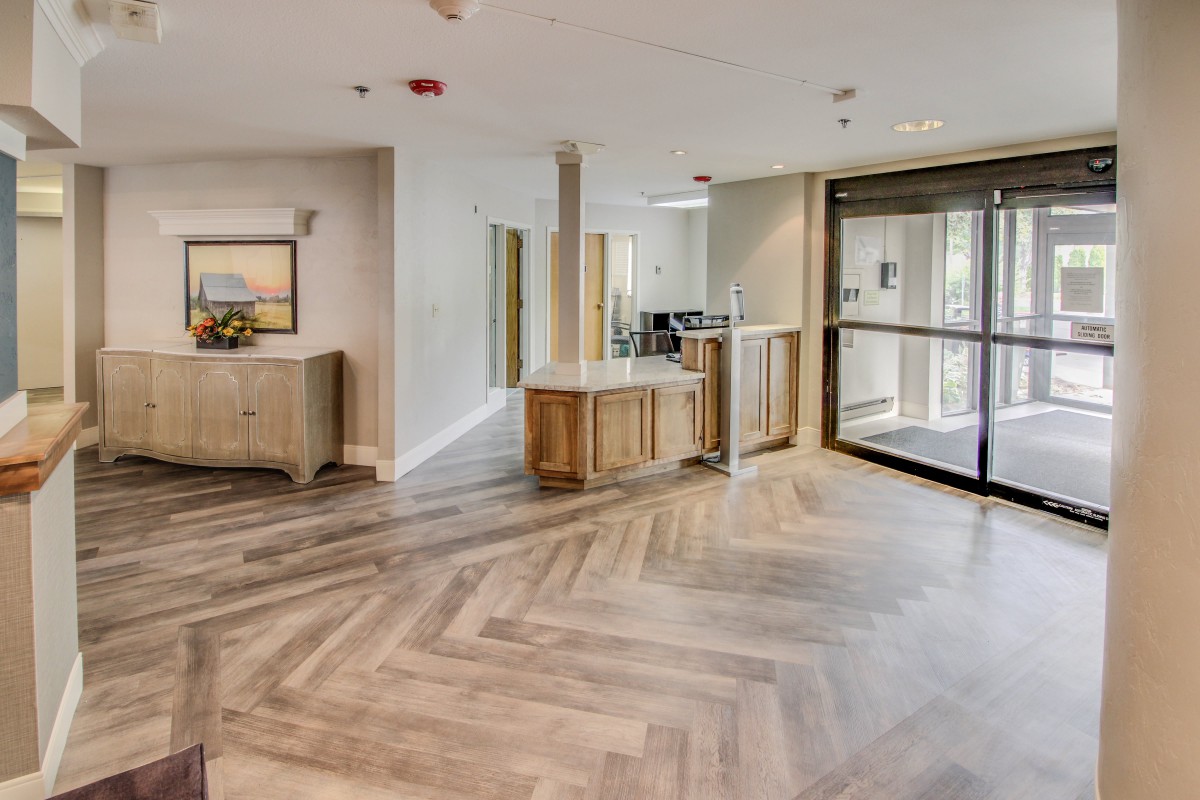 A modern lobby area with wooden flooring and a reception desk.
