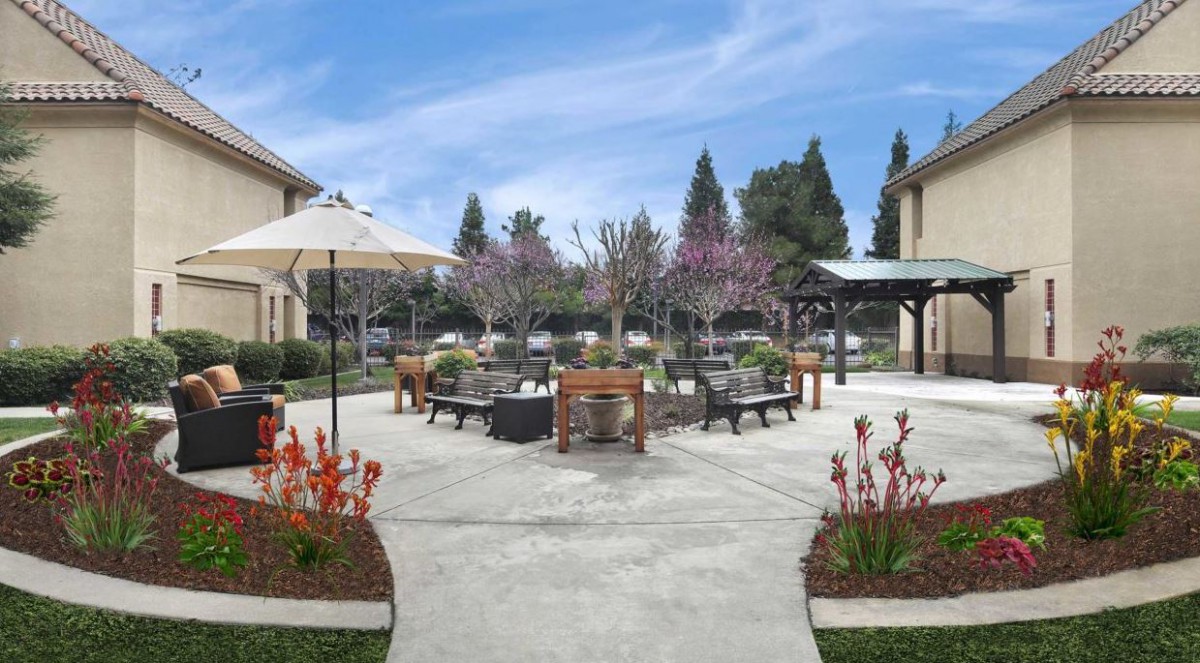 A beautifully landscaped courtyard with outdoor furniture and colorful flowers.